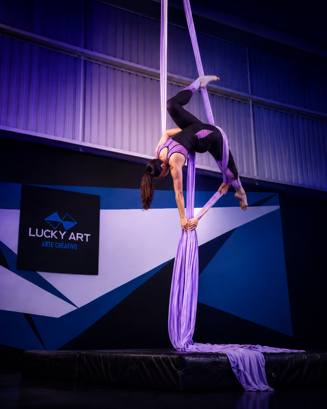 Estudiante de danza aérea en telas frente al muro Lucky Art